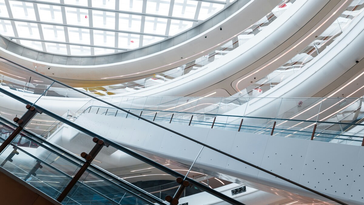 Escalators and curved balconies inside a bright modern shopping mall in Pudong, Shanghai.