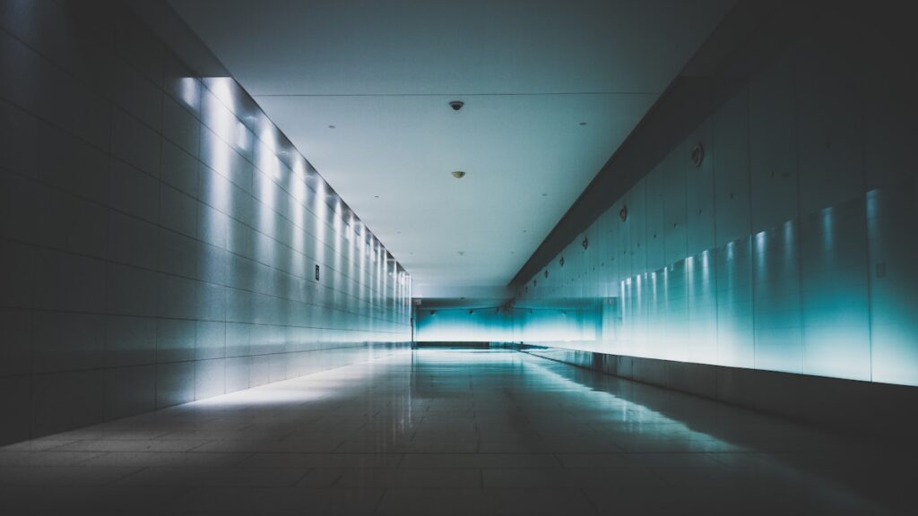 A symmetrical underground corridor lit blue, receding towards a bright doorway in Montreal.